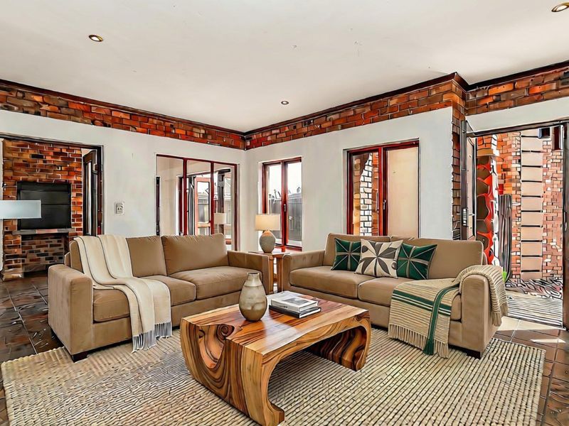 Spacious living room featuring exposed brick accents, tiled flooring, and multiple sliding glass doors providing access to the outdoor area.