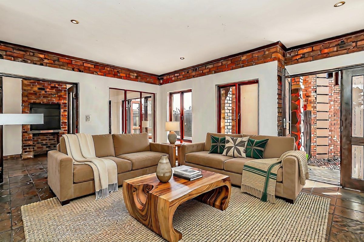 Spacious living room featuring exposed brick accents, tiled flooring, and multiple sliding glass doors providing access to the outdoor area.