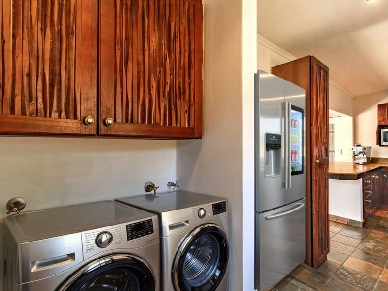 A functional laundry area featuring built-in wooden cabinetry and stone tile flooring, with direct access to the adjacent kitchen space.