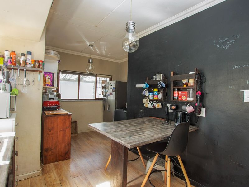 A kitchen area featuring laminate flooring, a prominent chalkboard wall, and pendant lighting, offering a functional space with potential for cosmetic updates.
