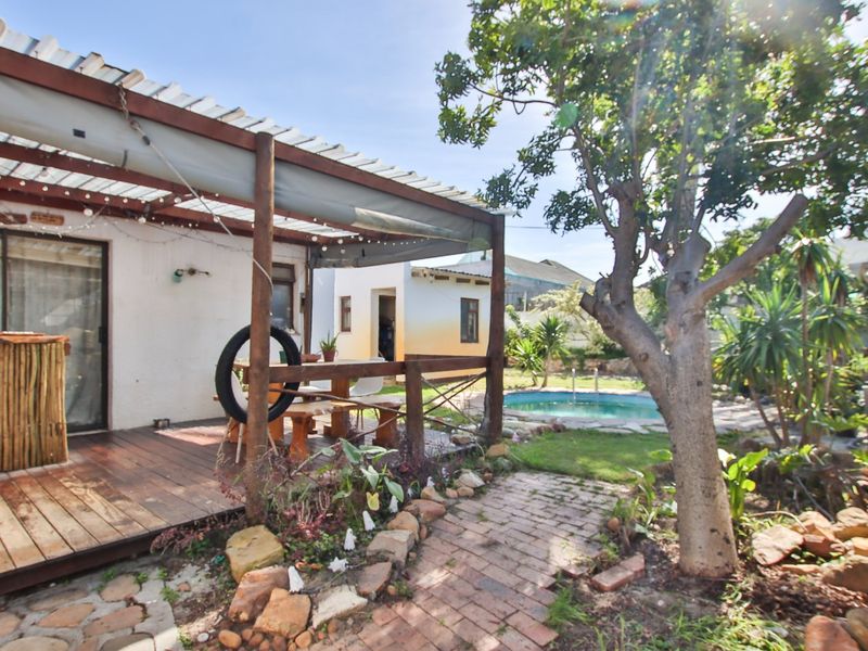 Outdoor entertainment area featuring a timber deck with a pergola, overlooking a swimming pool and garden space.