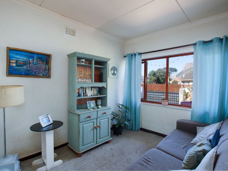 A cozy living room featuring a large window with natural light, textured walls, and carpeted flooring.