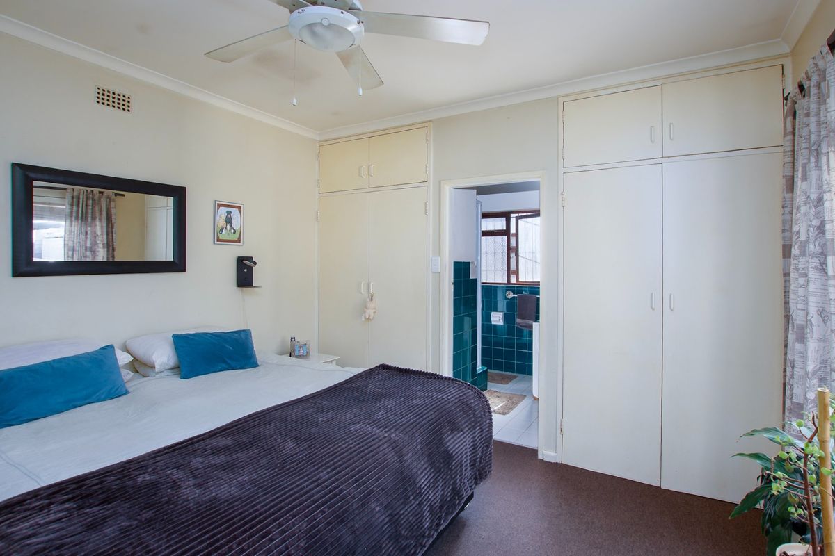 A bedroom featuring built-in cupboards, a ceiling fan, and direct access to an en-suite bathroom.
