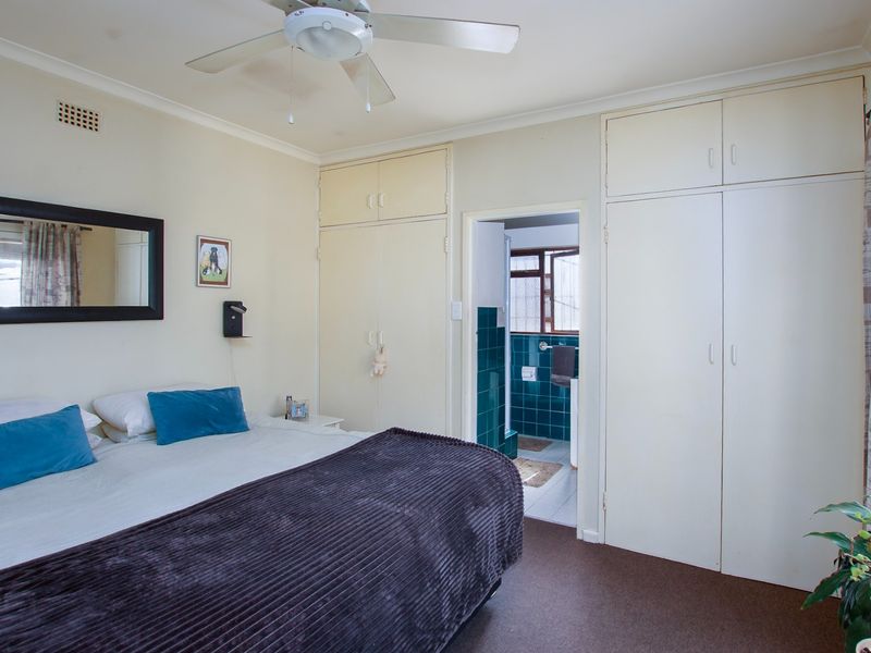 A bedroom featuring built-in cupboards, a ceiling fan, and direct access to an en-suite bathroom.