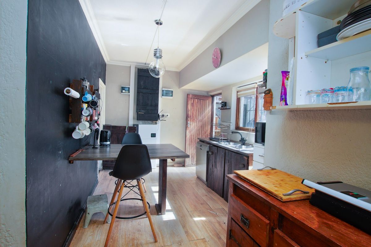 A compact kitchen area featuring wooden cabinetry, a stainless steel sink, and laminate flooring, offering potential for a modern renovation.