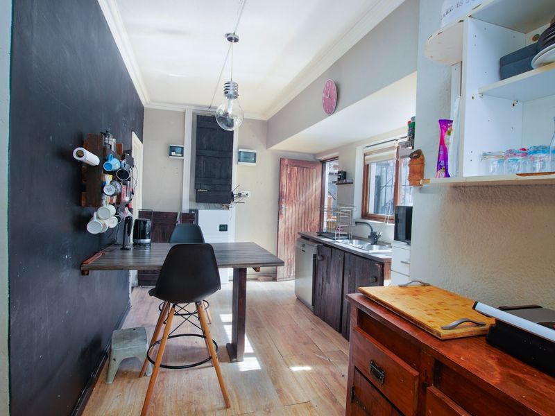 A compact kitchen area featuring wooden cabinetry, a stainless steel sink, and laminate flooring, offering potential for a modern renovation.
