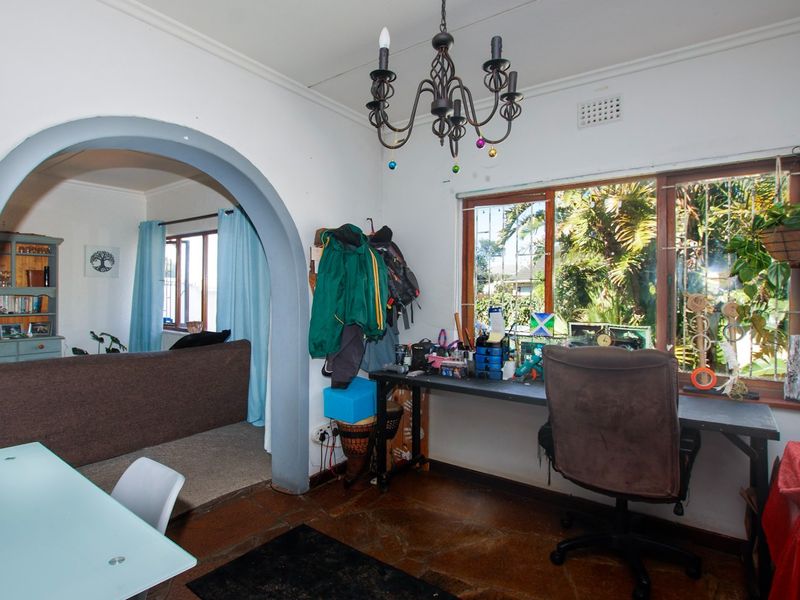 Living area featuring a distinctive arched entryway, terracotta flooring, and a wrought iron chandelier, providing a character-filled space with natural light.