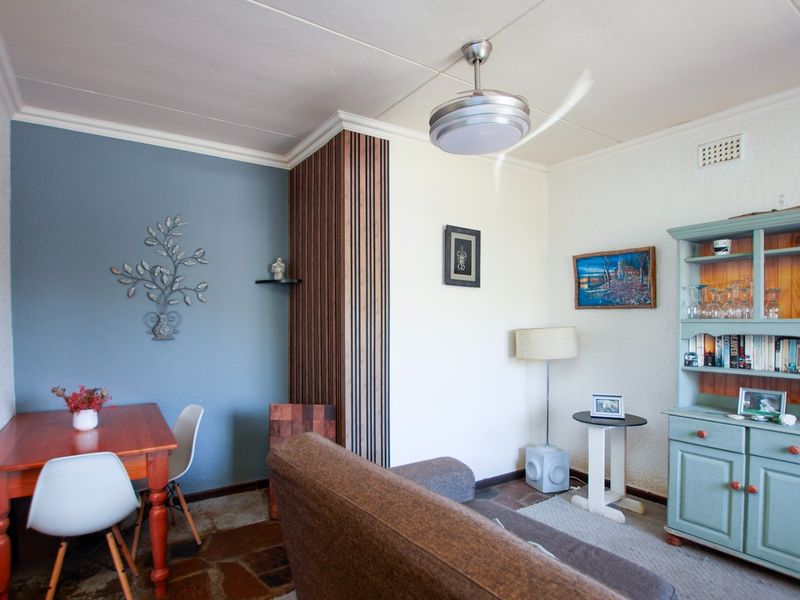 A living area featuring stone flooring, decorative wall paneling, and a ceiling fan, offering a cozy and functional space.