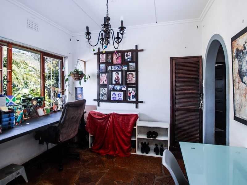 A functional home office space featuring a built-in desk, stone flooring, and an arched entryway, providing a versatile area for work or study.
