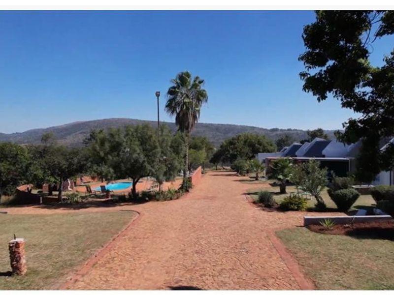 Spacious rear garden area featuring a swimming pool, paved driveway, and established landscaping with scenic mountain views.