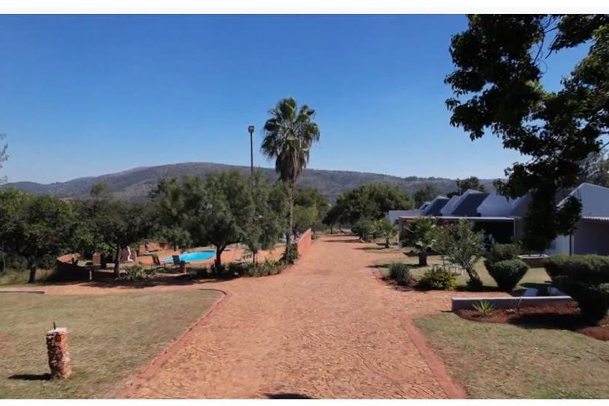 Spacious rear garden area featuring a swimming pool, paved driveway, and established landscaping with scenic mountain views.