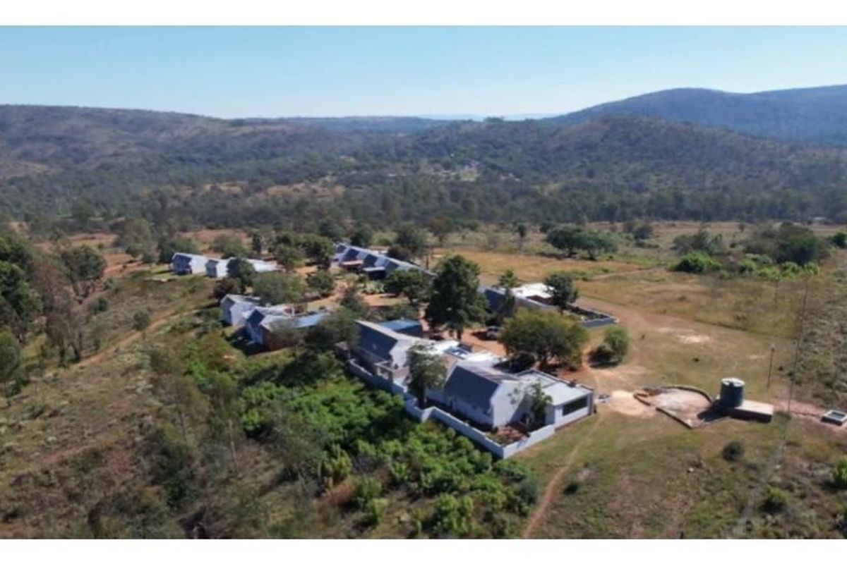 Aerial view of a rural property complex featuring multiple buildings with pitched metal roofs set within a vast, natural landscape.