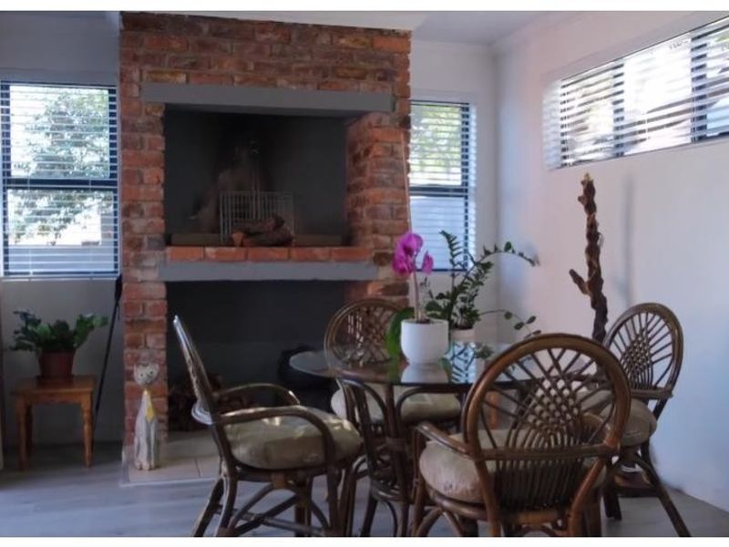 A bright living area featuring a prominent exposed brick fireplace, modern laminate flooring, and large sliding glass doors providing natural light.