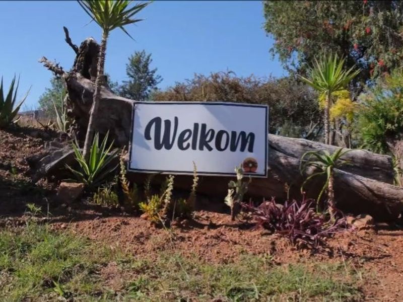 A landscaped garden area featuring a decorative log and welcome sign, showcasing the property's natural outdoor surroundings.