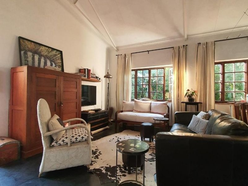 A cozy living room featuring a high vaulted ceiling, dark concrete flooring, and large timber-framed windows that provide ample natural light.