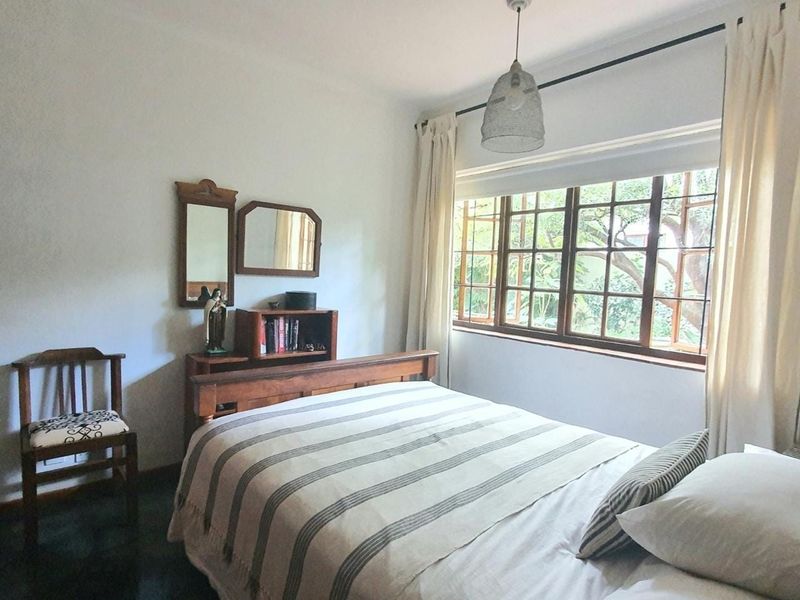 A cozy bedroom featuring timber-framed windows that provide natural light and a view of the garden.