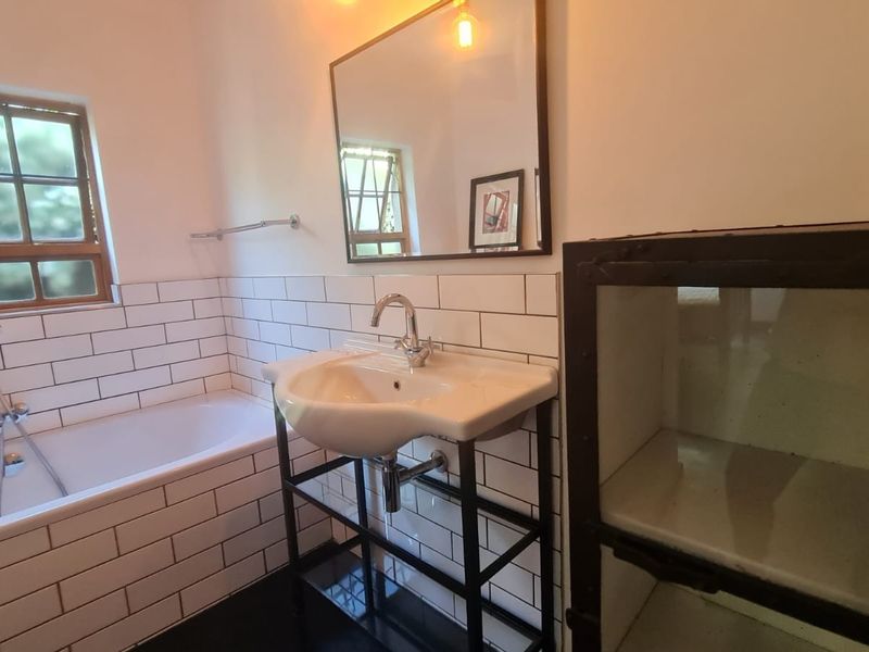 A modern bathroom featuring subway tile wall cladding, a pedestal washbasin with chrome fixtures, and a built-in bathtub with a handheld shower attachment.