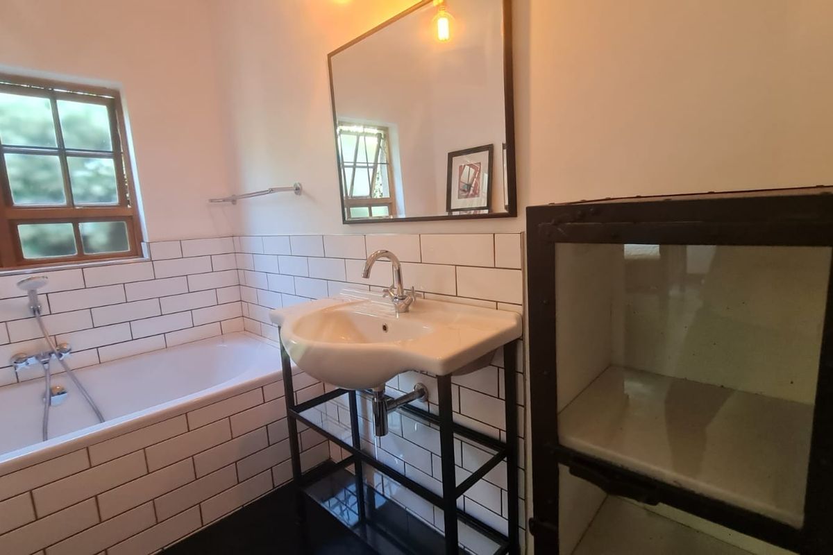 A modern bathroom featuring subway tile wall cladding, a pedestal washbasin with chrome fixtures, and a built-in bathtub with a handheld shower attachment.