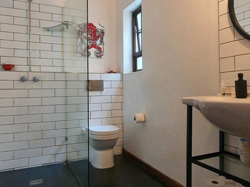 Modern bathroom featuring a walk-in shower with glass screen, subway tiling, wall-mounted toilet, and a sleek pedestal basin.