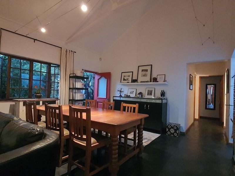 Spacious living area featuring a high vaulted ceiling with exposed rafters, timber-framed windows, and direct access to the exterior.