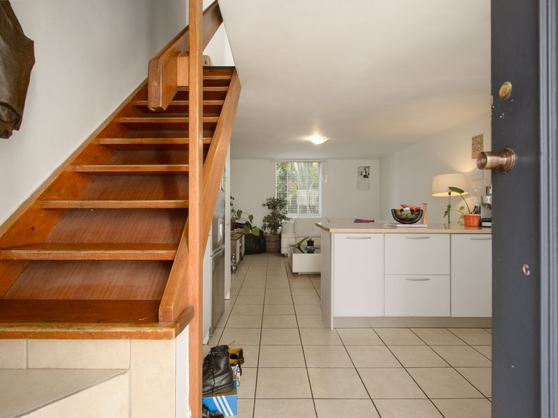 Open plan living area featuring a wooden staircase, tiled flooring, and a functional kitchen island with modern cabinetry.