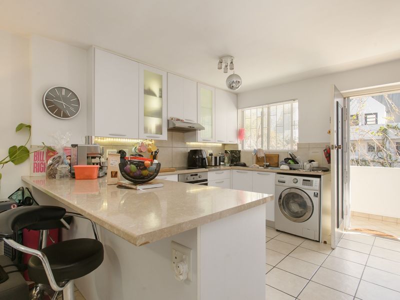 Functional kitchen featuring white cabinetry, stone countertops, a breakfast bar, integrated appliances, and direct access to an outdoor balcony area.