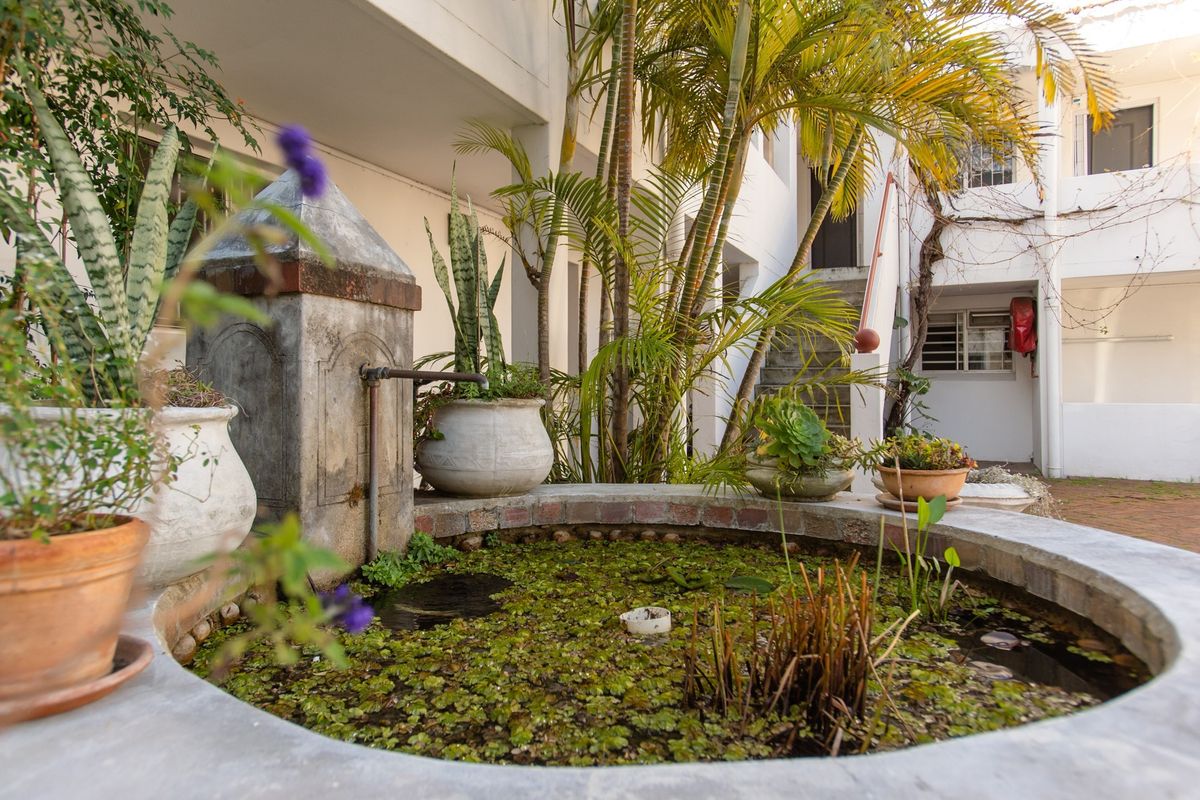 A courtyard area featuring a stone water fountain, brick paving, and access to an external concrete staircase within an apartment complex.