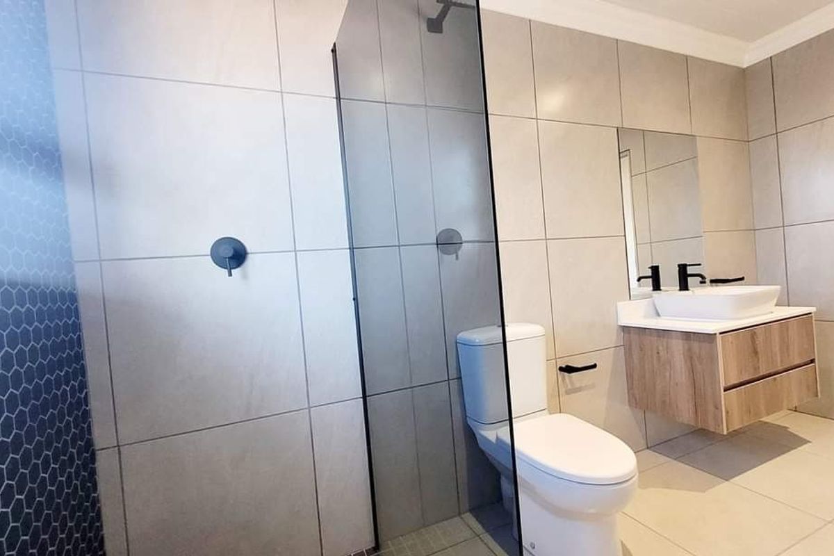 Modern bathroom featuring a walk-in shower with glass screen, wall-mounted vanity with vessel sink, and contemporary black matte fixtures.