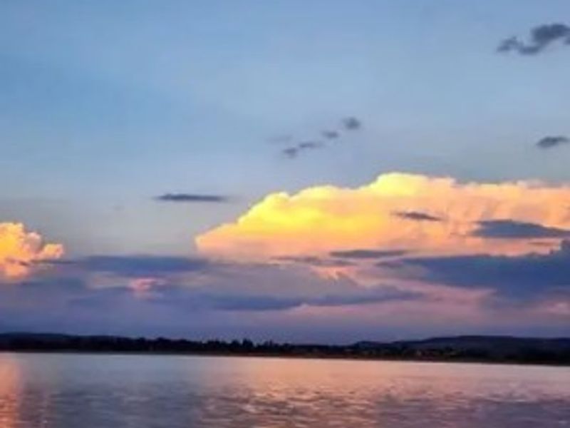 A scenic view of a calm body of water at sunset with colorful clouds.