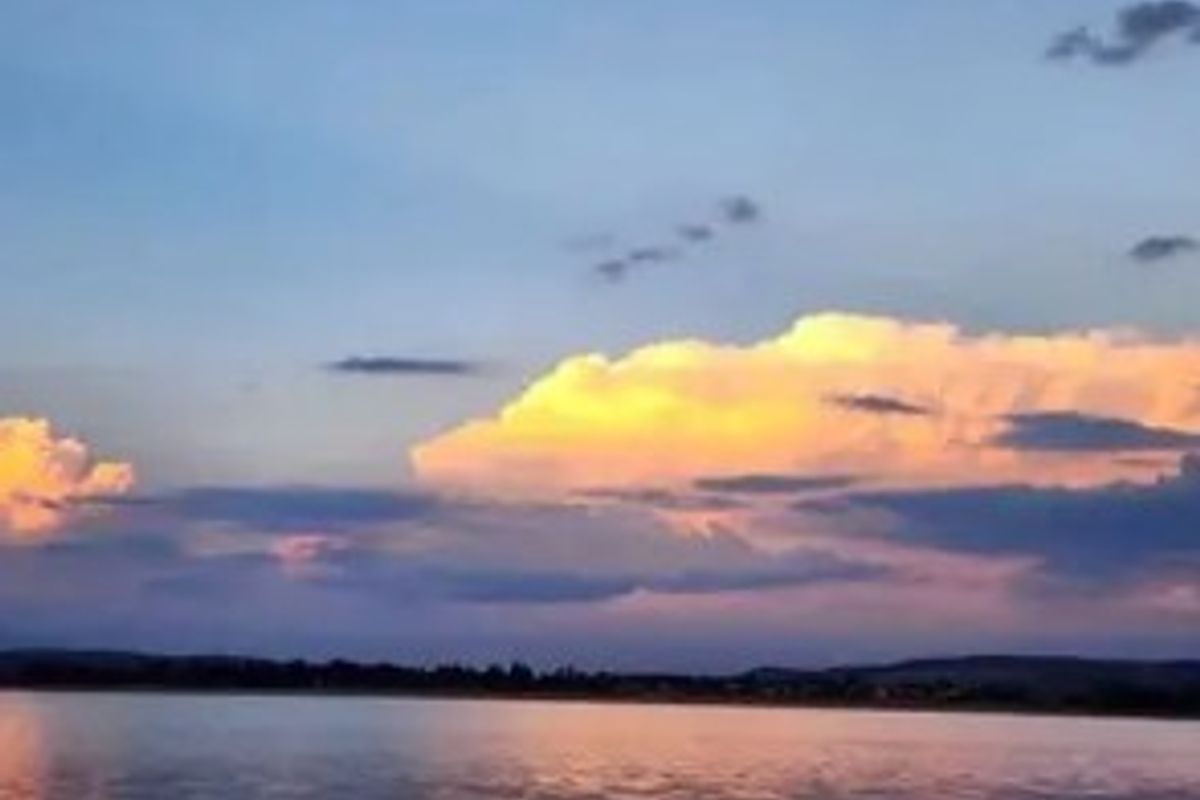 A scenic view of a calm body of water at sunset with colorful clouds.