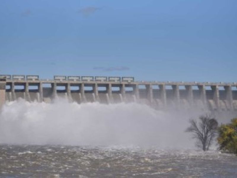 A scenic view of a large dam structure with water flowing over the spillway.