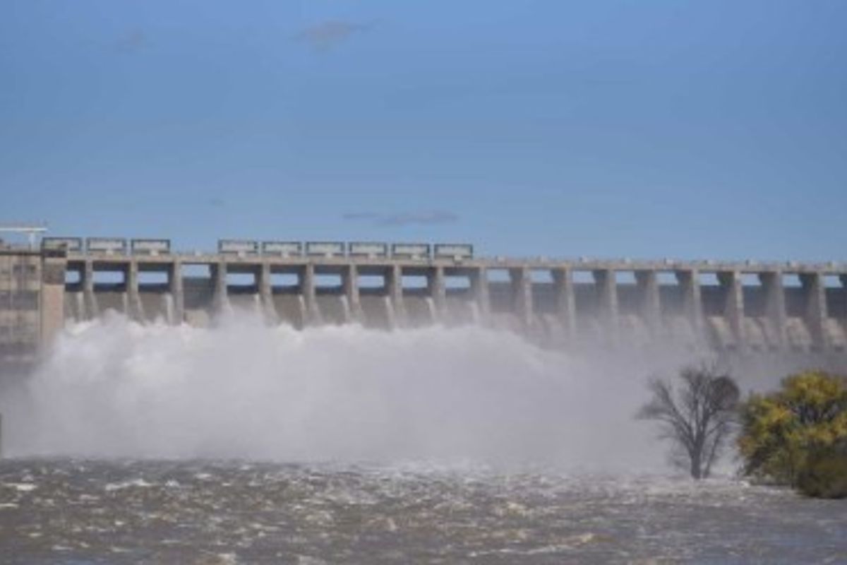A scenic view of a large dam structure with water flowing over the spillway.