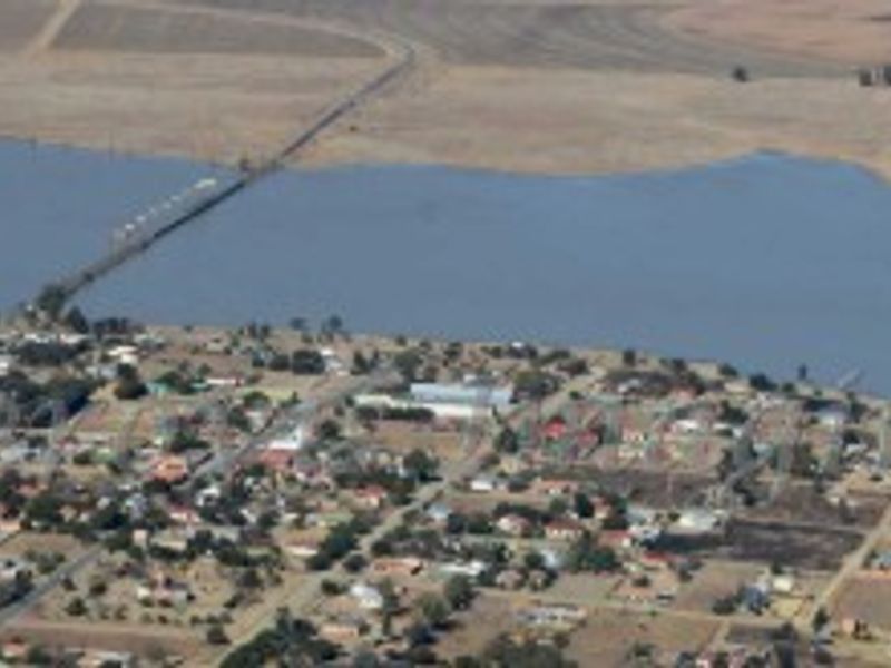 An aerial view of a residential area situated along a waterfront, showing the surrounding landscape and local road infrastructure.