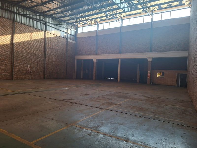 Spacious industrial warehouse unit featuring high ceilings, exposed brickwork, durable concrete flooring, and ample natural light through high-level windows.