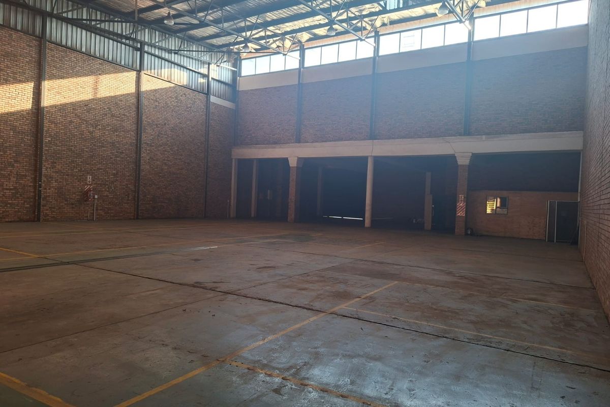 Spacious industrial warehouse unit featuring high ceilings, exposed brickwork, durable concrete flooring, and ample natural light through high-level windows.