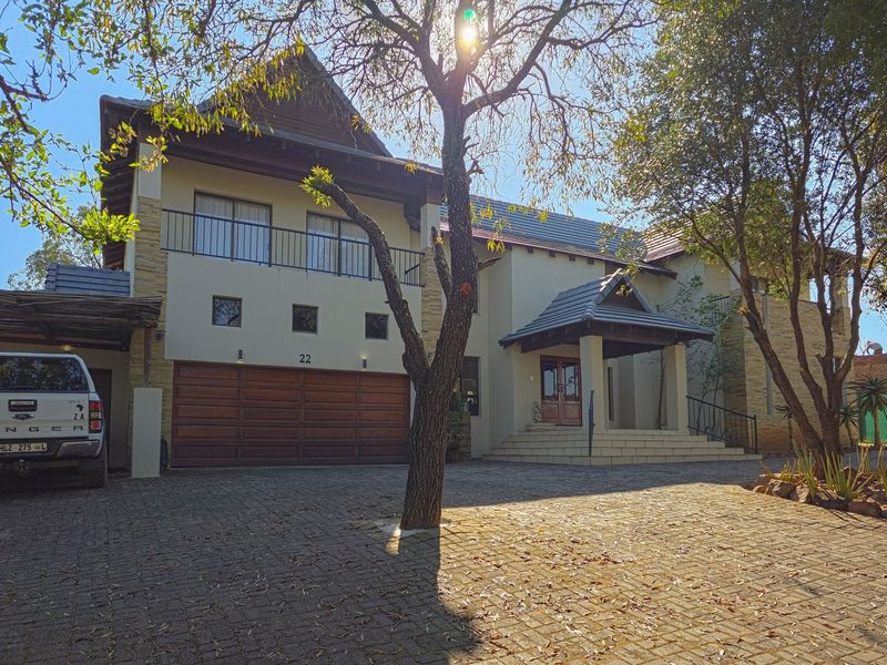 A well-maintained double-story residential property featuring a paved driveway, double garage, stone cladding accents, and a covered entrance porch.