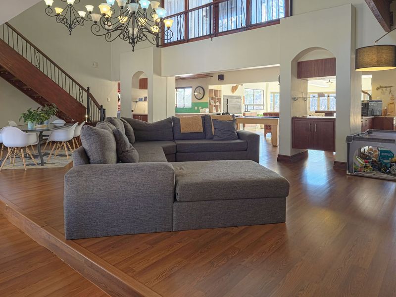 Spacious open-plan living area featuring hardwood floors, a grand staircase with wrought iron railings, and a mezzanine level overlooking the main lounge.