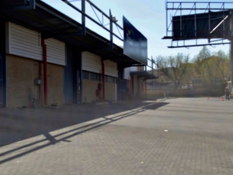 Industrial property exterior featuring a paved yard, steel structural framing, and multiple roller shutter access points.