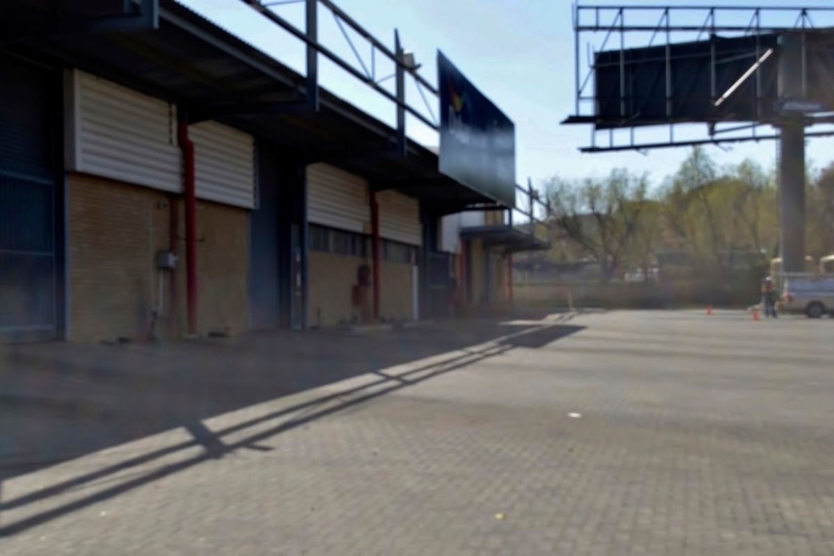 Industrial property exterior featuring a paved yard, steel structural framing, and multiple roller shutter access points.