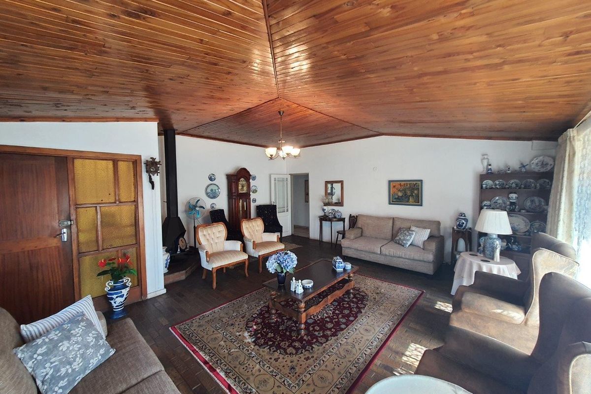Spacious living room featuring a distinctive timber-clad vaulted ceiling, tiled flooring, and a cozy freestanding fireplace, offering a warm and traditional atmosphere.