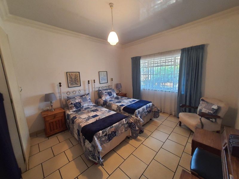 A bedroom featuring ceramic tile flooring, a window with security bars, and classic cove cornicing, providing a functional and well-lit sleeping space.