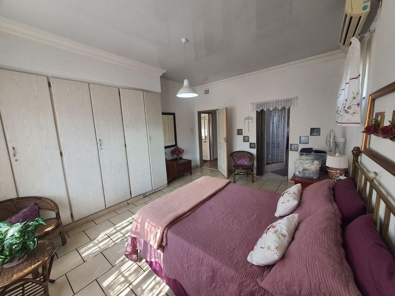 Spacious bedroom featuring built-in cupboards, tiled flooring, and an integrated air conditioning unit, offering a functional and comfortable living space.