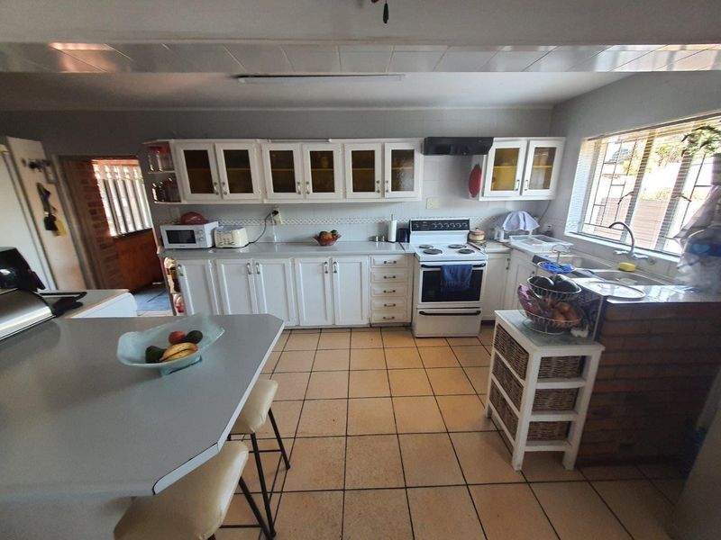 Functional kitchen featuring white cabinetry, laminate countertops, a freestanding stove, and tiled flooring with a breakfast nook area.