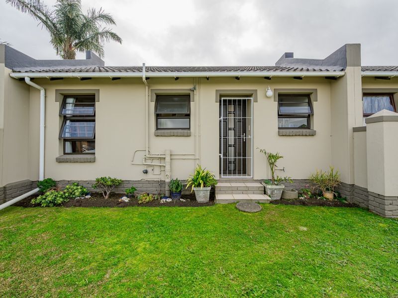 Rear elevation of the property featuring a small garden, security gate entrance, and top-hung windows with a tiled roof finish.