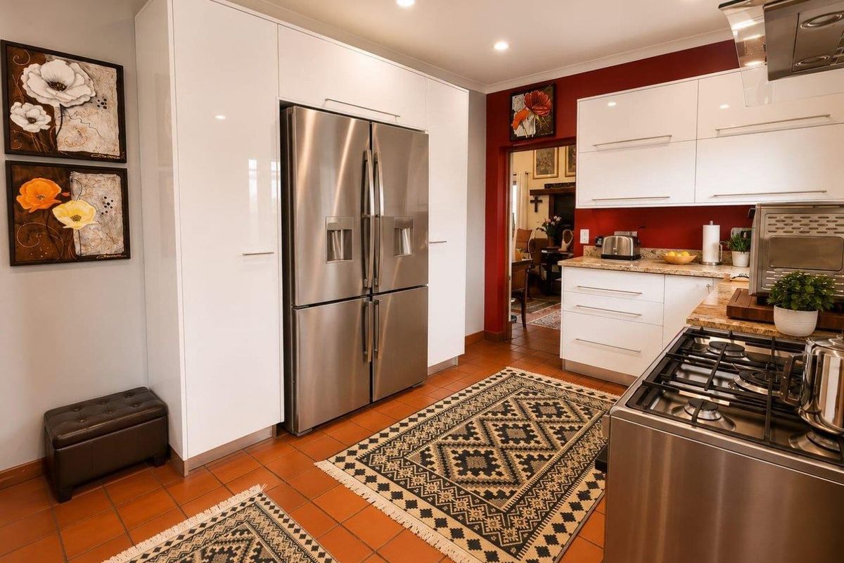 A well-maintained kitchen featuring modern white cabinetry, stainless steel appliances, a gas cooktop, and durable tiled flooring.