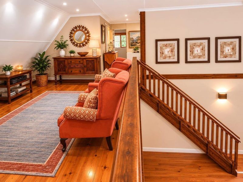 A well-maintained upper-level landing area featuring polished timber flooring, a classic timber staircase with balustrade, and a sloped ceiling with recessed lighting.