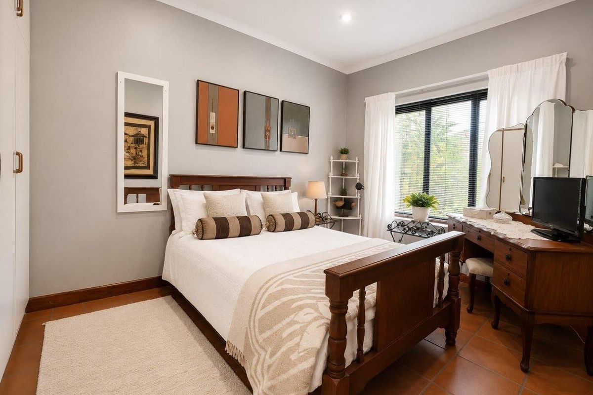 A well-maintained bedroom featuring tiled flooring, recessed downlighting, and a built-in wardrobe, offering a comfortable and functional living space.