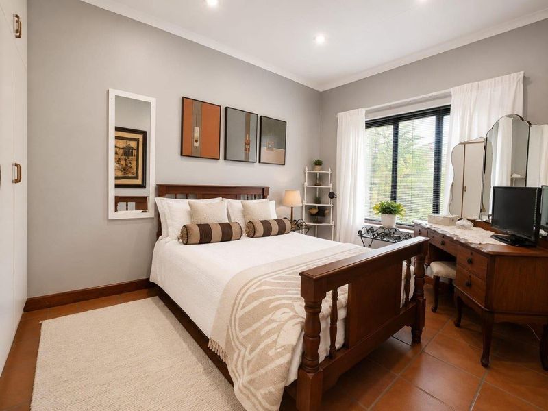 A well-maintained bedroom featuring tiled flooring, recessed downlighting, and a built-in wardrobe, offering a comfortable and functional living space.