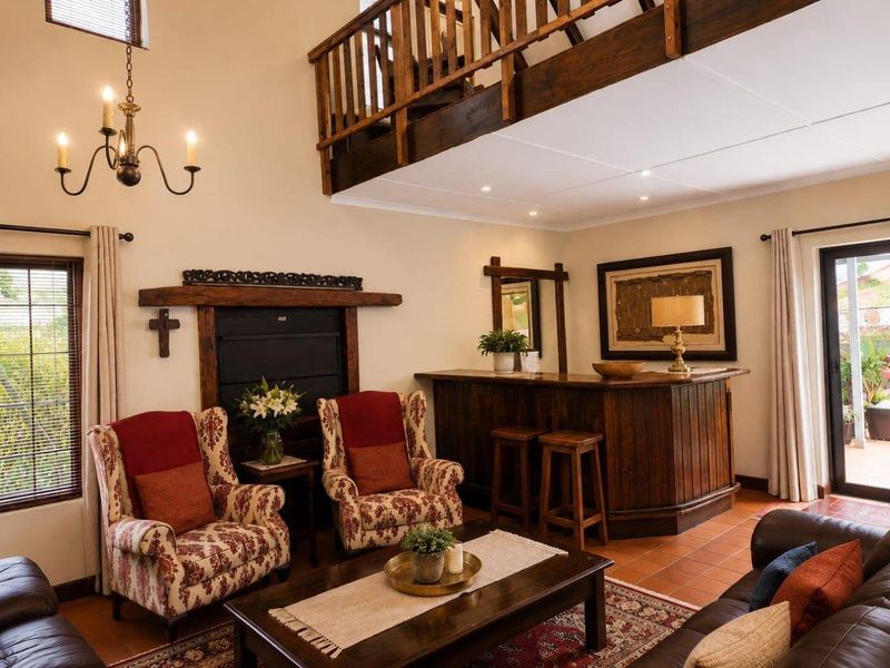 Spacious living room featuring a built-in fireplace, a custom wooden bar, terracotta flooring, and a mezzanine level with a wooden balustrade.