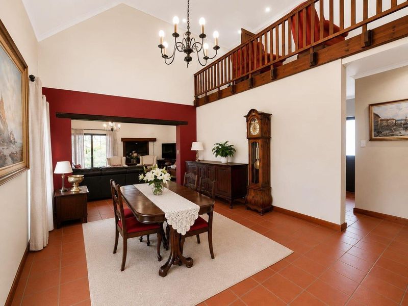 Spacious dining area featuring a vaulted ceiling, terracotta floor tiles, and a mezzanine balcony with a timber balustrade overlooking the room.